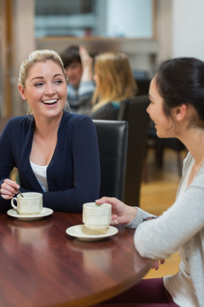 Women sitting at the coffee shop smiling and chatting